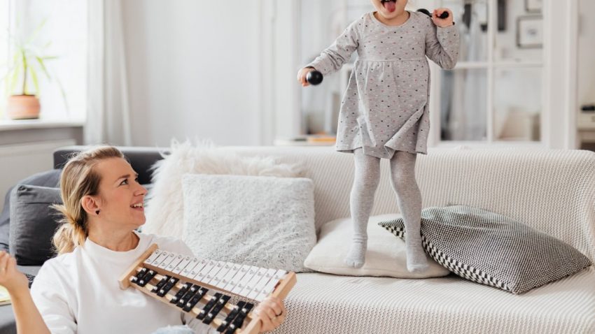 Fun indoor scene of a mother and daughter playing with a xylophone, creating joyful memories.